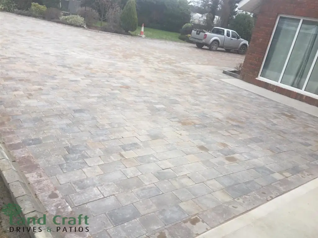Grey block paved driveway beside a house