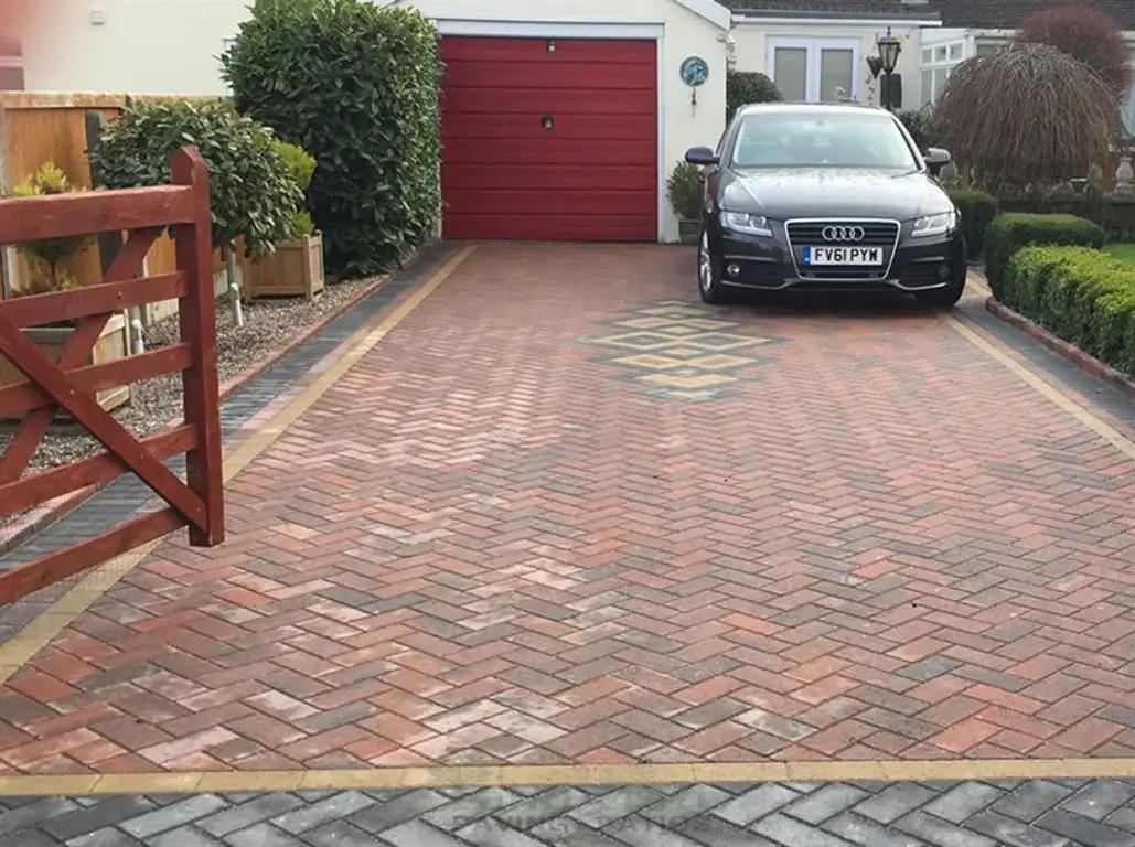 Red herringbone block paved driveway with a car parked