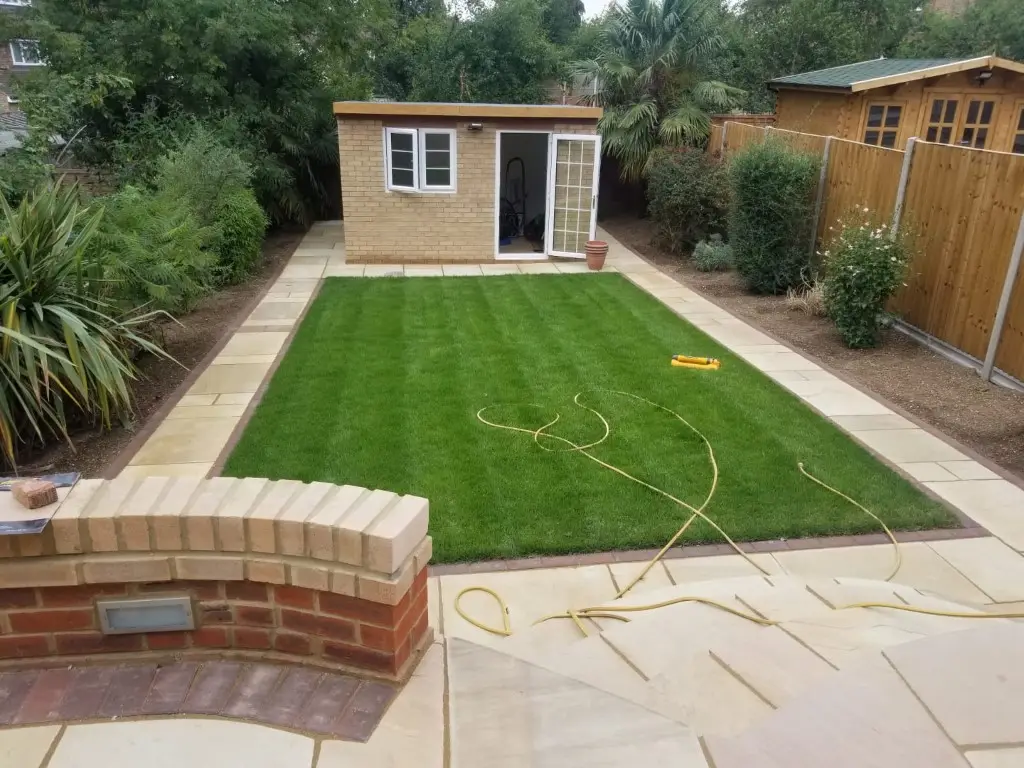 Landscaped garden with a striped lawn and sandstone paving