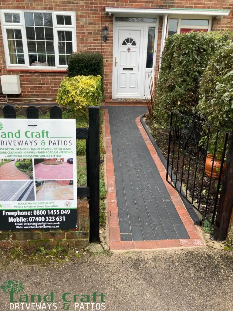 Charcoal block path with a red border beside railings
