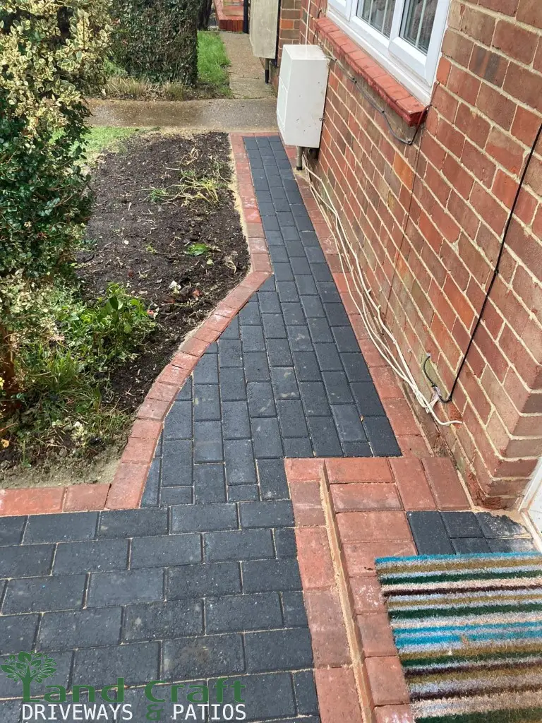 Charcoal block paving with a red border around a house
