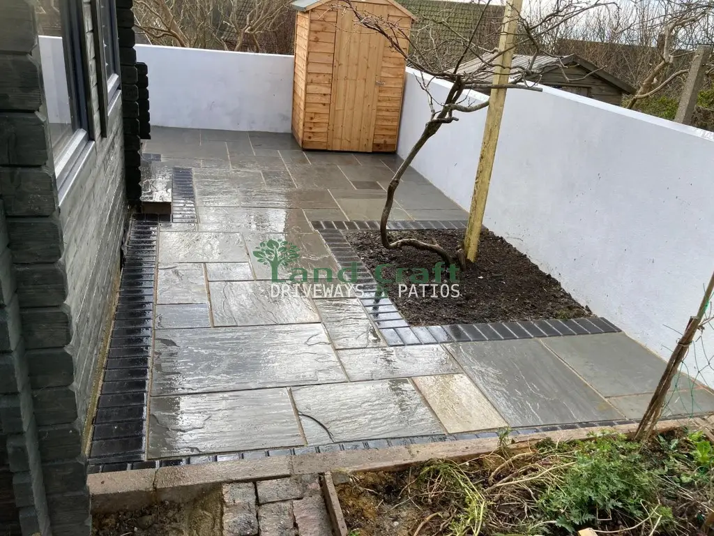 Grey paving along the side of a house