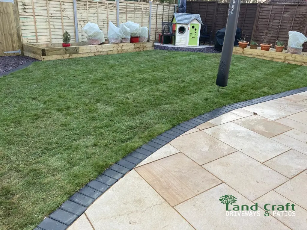 Buff porcelain patio curving around a new lawn